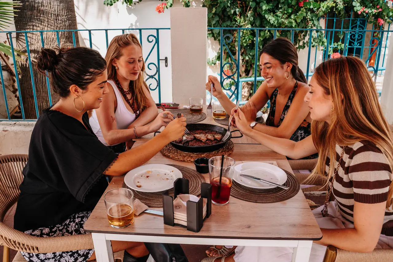 Grupo de amigas comiendo en la terraza entre buganvillas