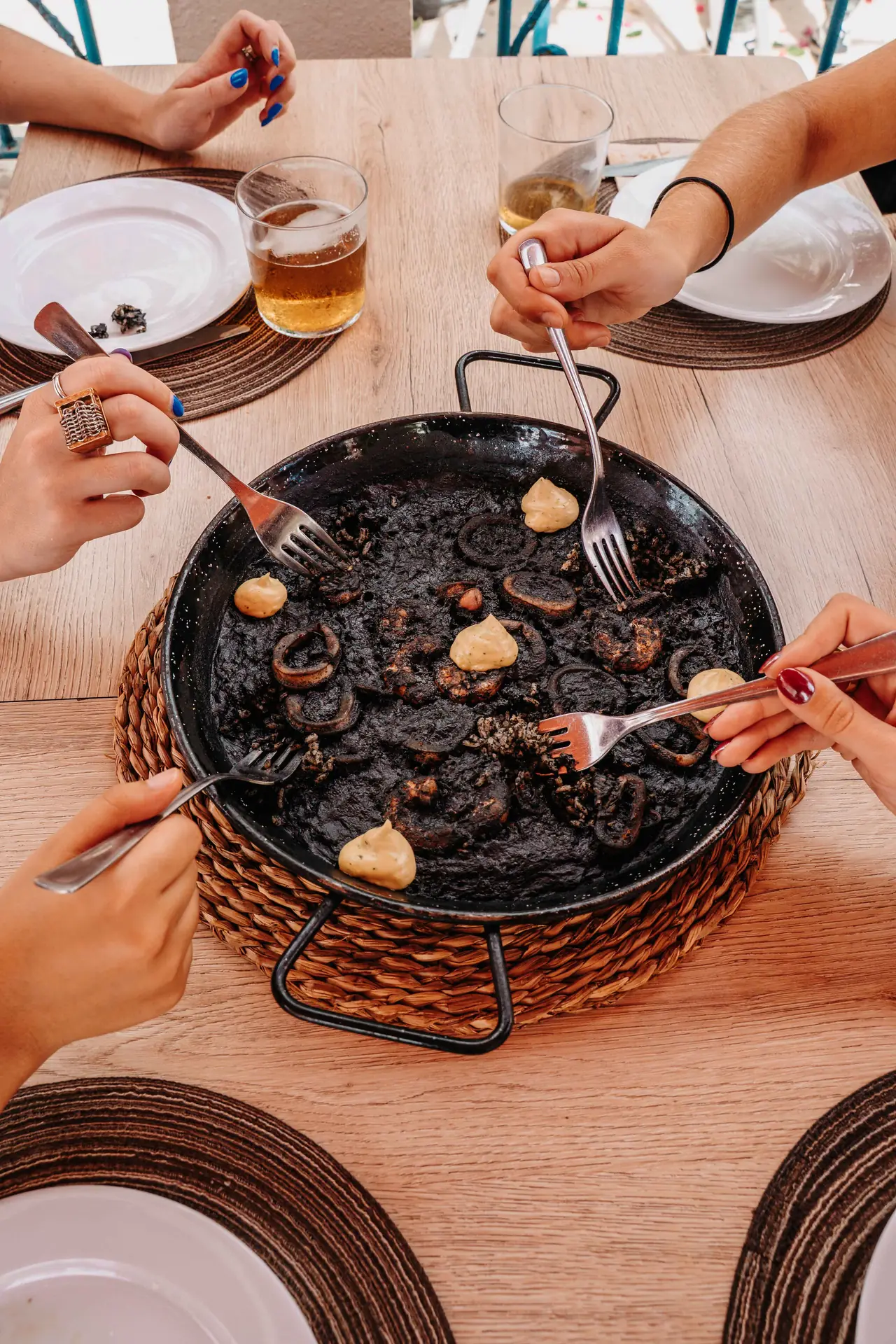Manos sirviendo arroz negro en la mesa